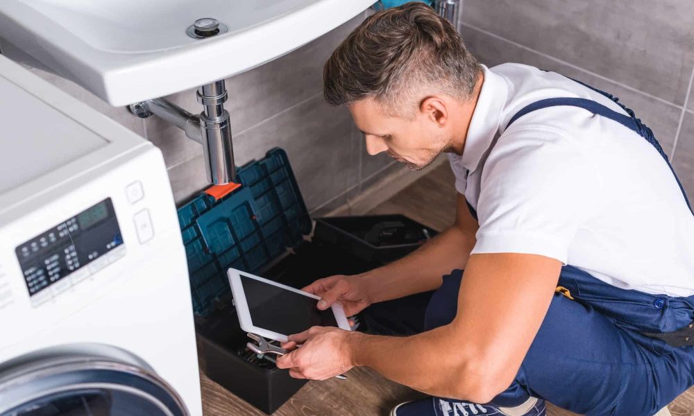 adult-repairman-sitting-on-floor-and-using-digital-tablet-while-repairing-sink-at-bathroom.jpg